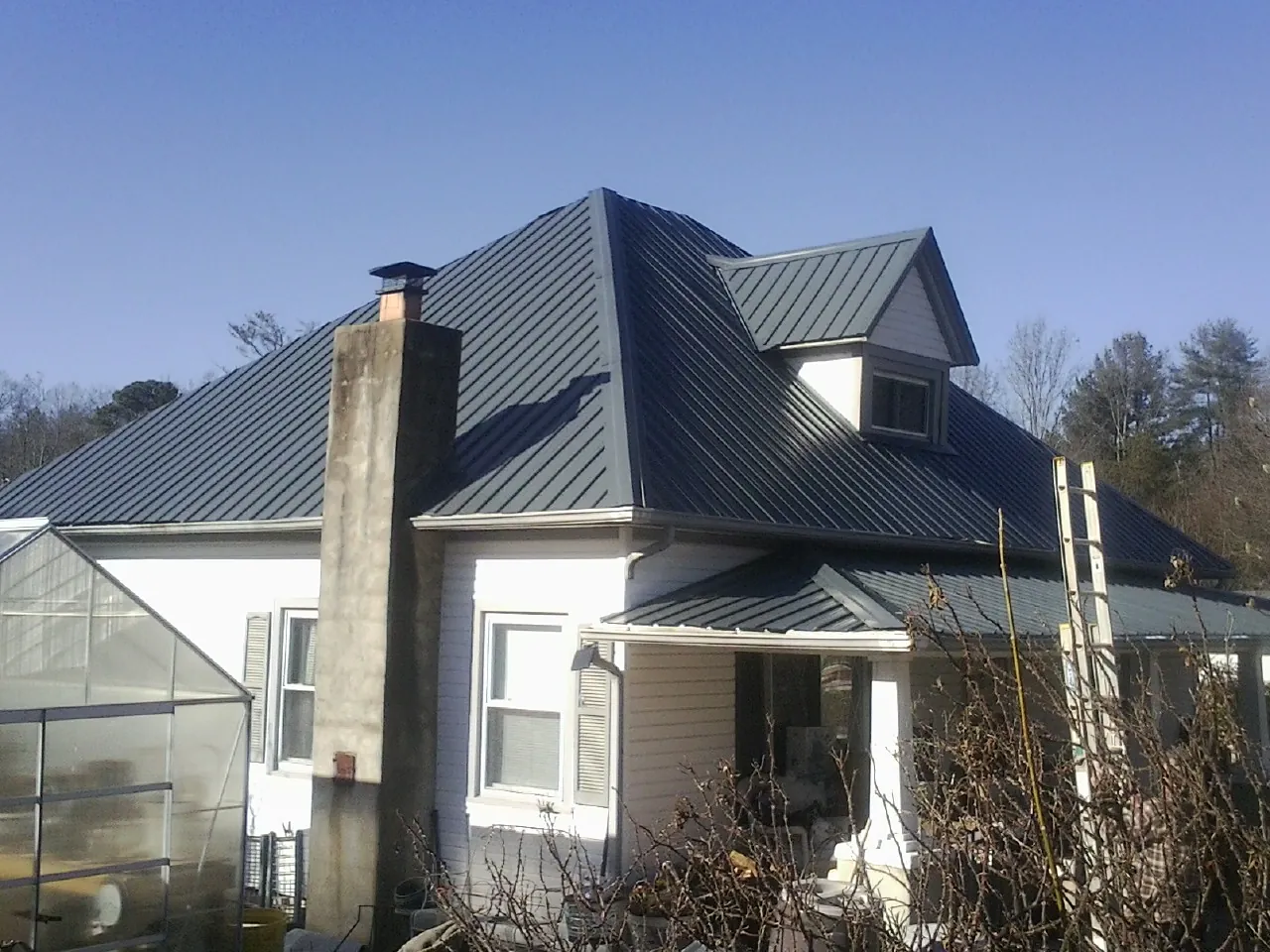 Dark blue standing seam metal roof on a white farmhouse with dormer — Slate & Tile Roof Repair by Roofing Brothers in White Marsh