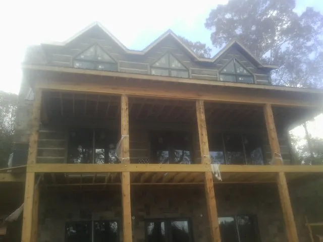 Dormers and porch framing on a large log home under construction — Roof Coating work by our crew in White Marsh