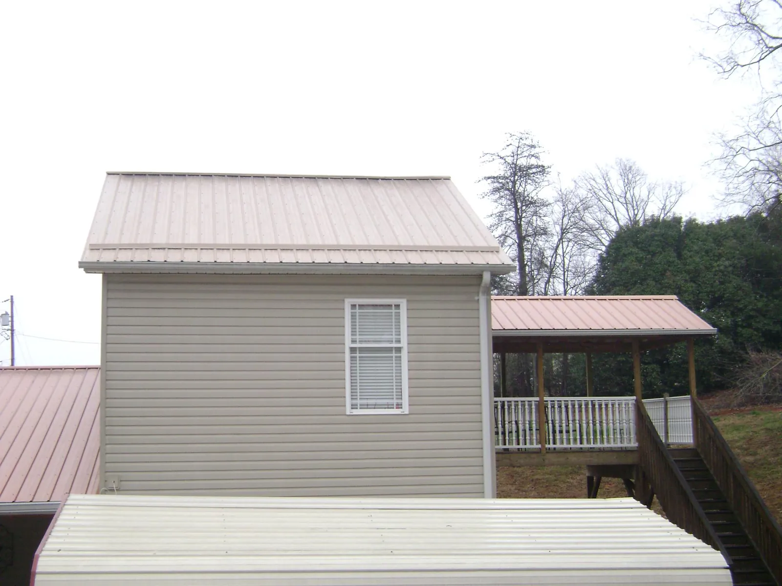 Tan metal roofs on a two story addition and attached porch, from a Roof Replacement job in White Marsh