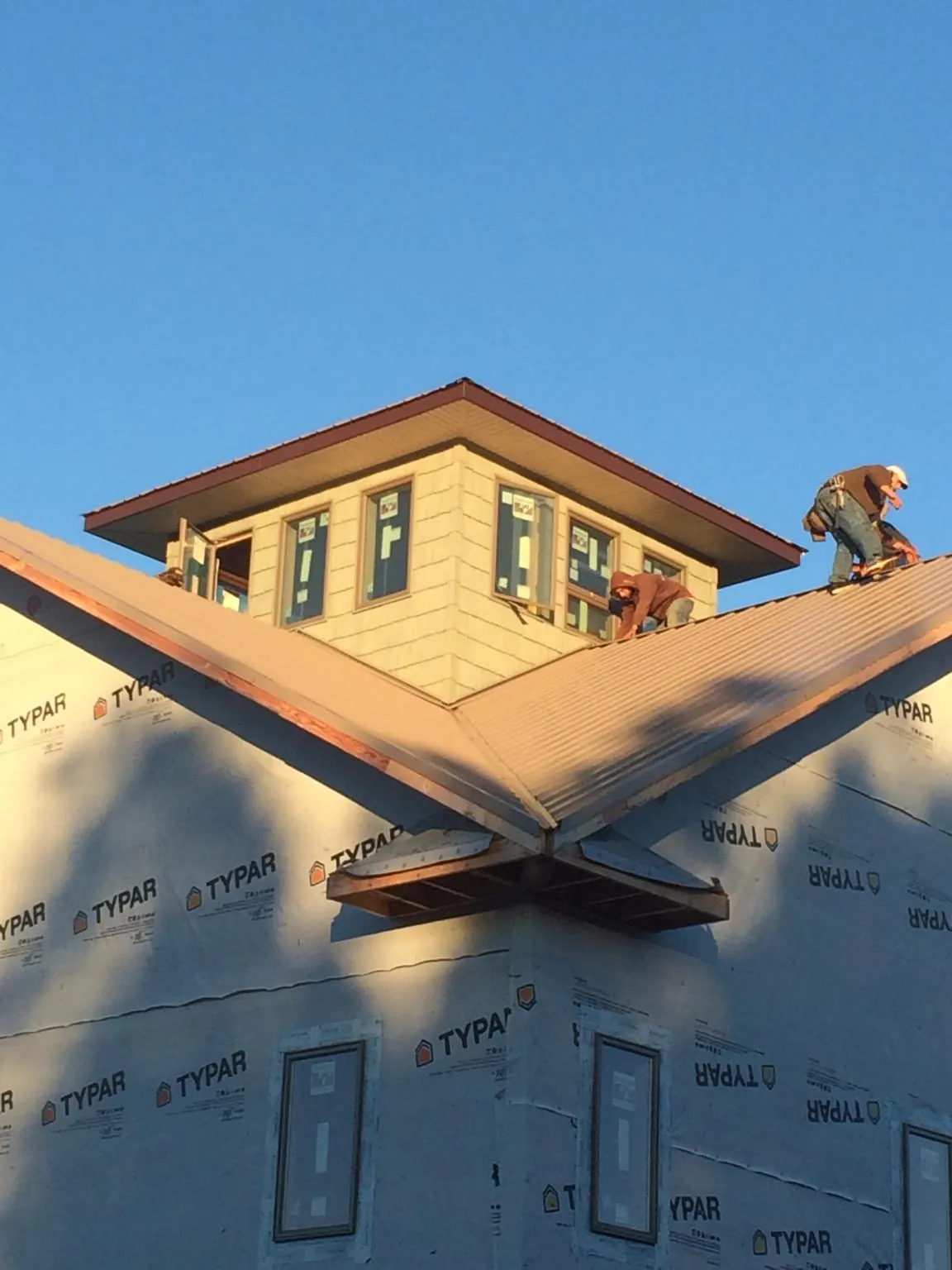 Roofers working around a rooftop cupola on a new metal roof at sunset — Roof Waterproofing in White Marsh by Roofing Brothers